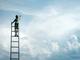 Figuur op hoge ladder reikt naar de wolkenlucht, symbolische weergave van ambitie en het najagen van dromen