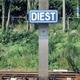 Stationsnaambord "Diest" langs spoorlijn, omringd door groen landschap en spoorinfrastructuur