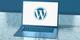 Laptop met WordPress-logo op het scherm, getoond op een reflecterende ondergrond met blauwe tint