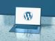 Laptop met WordPress-logo op het scherm, getoond op een reflecterende ondergrond met blauwe tint
