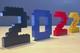 Het jaartal 2022 gebouwd met LEGO stenen in zwart, blauw, rood en geel op een houten ondergrond