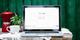 Laptop met Google-startpagina op scherm, naast rode koffiepot en witte kop op rustieke houten tafel met kanten kleed