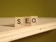 Houten Scrabble-letters vormen het woord "SEO" op een schuin oppervlak met groene achtergrond