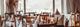 Elegant gedekte tafels in restaurant met houten stoelen, witte tafellinnen en groot raam met uitzicht op bergen.