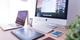 Modern werkstation met iMac, laptop, tekentablet en smartphone op houten bureau met witte bureaulamp