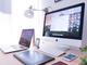 Modern werkstation met iMac, laptop, tekentablet en smartphone op houten bureau met witte bureaulamp