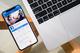 iPhone met Facebook-app open naast een MacBook op een houten tafel, zakelijke werkopstelling