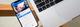 iPhone met Facebook-app open naast een MacBook op een houten tafel, zakelijke werkopstelling