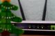 Een wifi-router met brandende statuslampjes, gedeeltelijk zichtbaar met een decoratieve kerstboom op de achtergrond