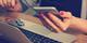 Handen met roze nagellak houden smartphone vast bij laptop op houten bureau, informele werkplek setting