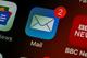 Close-up van een e-mail app icoon met 2 ongelezen berichten, getoond op een donker smartphonescherm naast andere apps