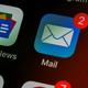 Close-up van een e-mail app icoon met 2 ongelezen berichten, getoond op een donker smartphonescherm naast andere apps