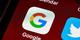 Close-up van mobiele app-iconen op een smartphone scherm, met focus op het kleurrijke Google-logo tussen Calendar en Twitter