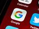 Close-up van mobiele app-iconen op een smartphone scherm, met focus op het kleurrijke Google-logo tussen Calendar en Twitter
