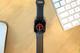 Zwarte Apple Watch Nike met rood wijzerplaat op houten bureau naast Magic Mouse en toetsenbord
