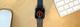 Zwarte Apple Watch Nike met rood wijzerplaat op houten bureau naast Magic Mouse en toetsenbord