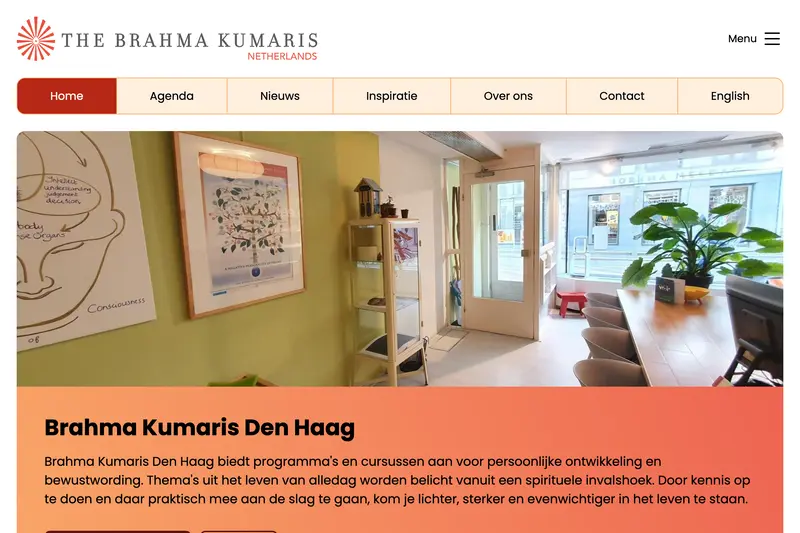 Lichte, uitnodigende entreehal van Brahma Kumaris Den Haag met groene muren, planten en meditatieve kunst aan de wand.